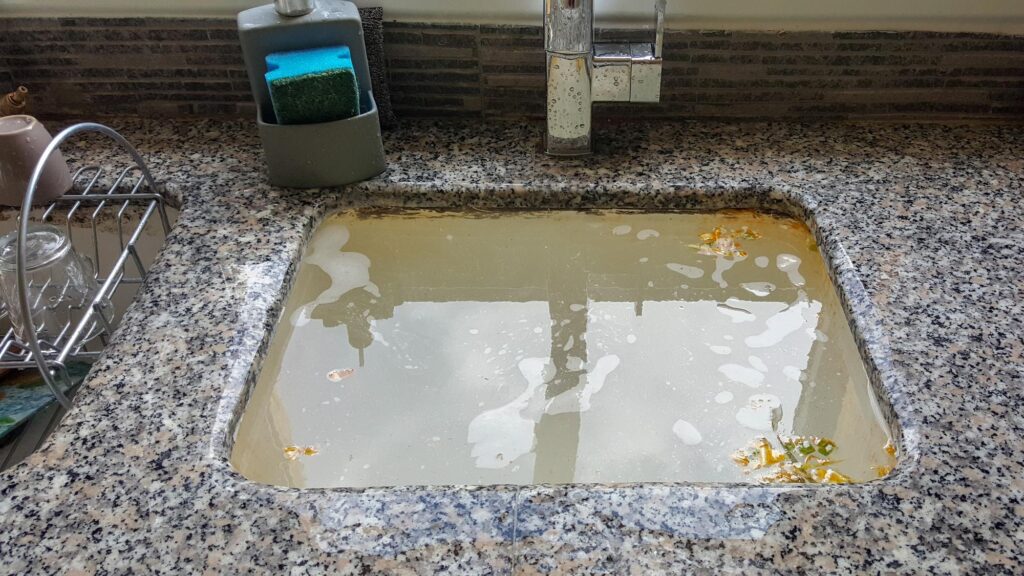 Clogged drains. Kitchen sink filled with water because of clogged drains.