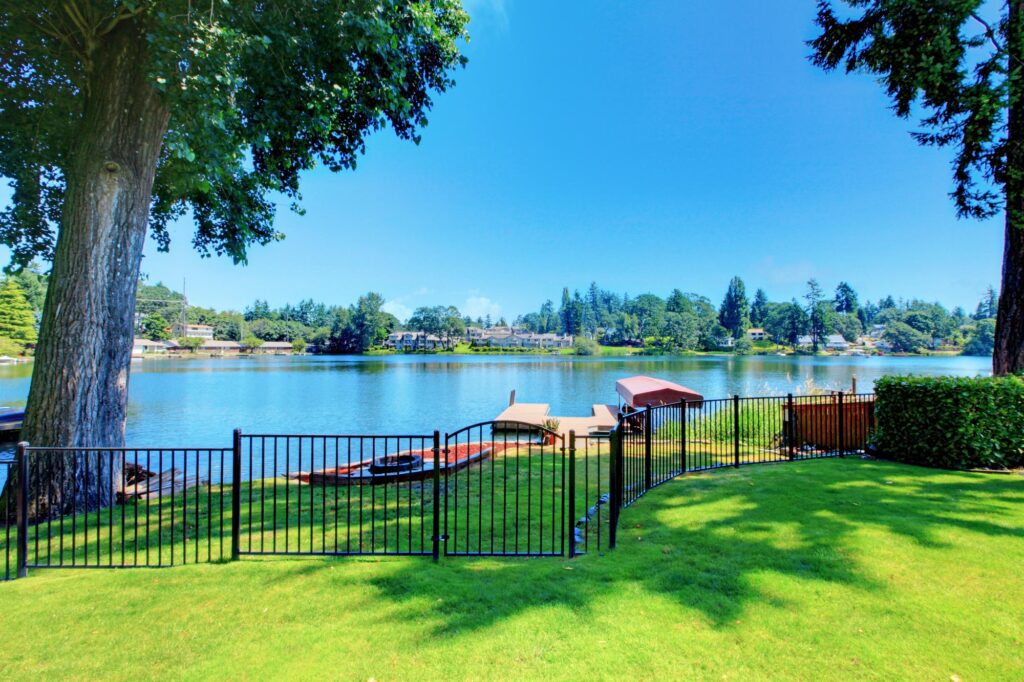 housing market trends - Backyard area with well kept lawn and black metal fence. Beautiful water view