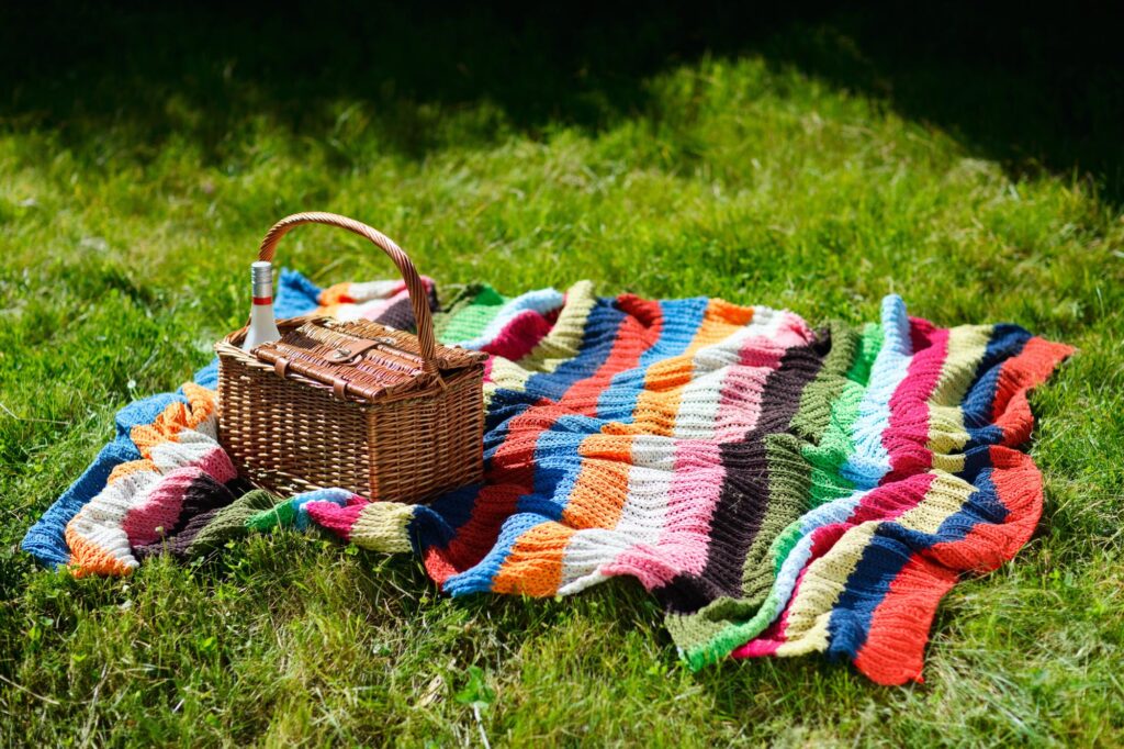 Picnic blanket and basket on green grass on a sunny day